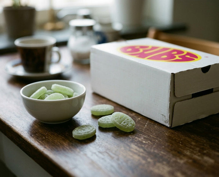 BUBS Cool Fruity Pear Medium oval-shaped green sour foam candies in a bowl next to the bulk storpack bag on a wooden table
