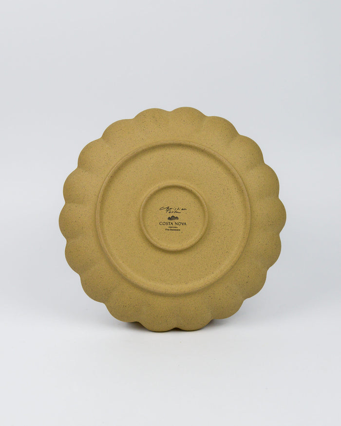 Stoneware ceramic plate with scalloped edge on a white background
