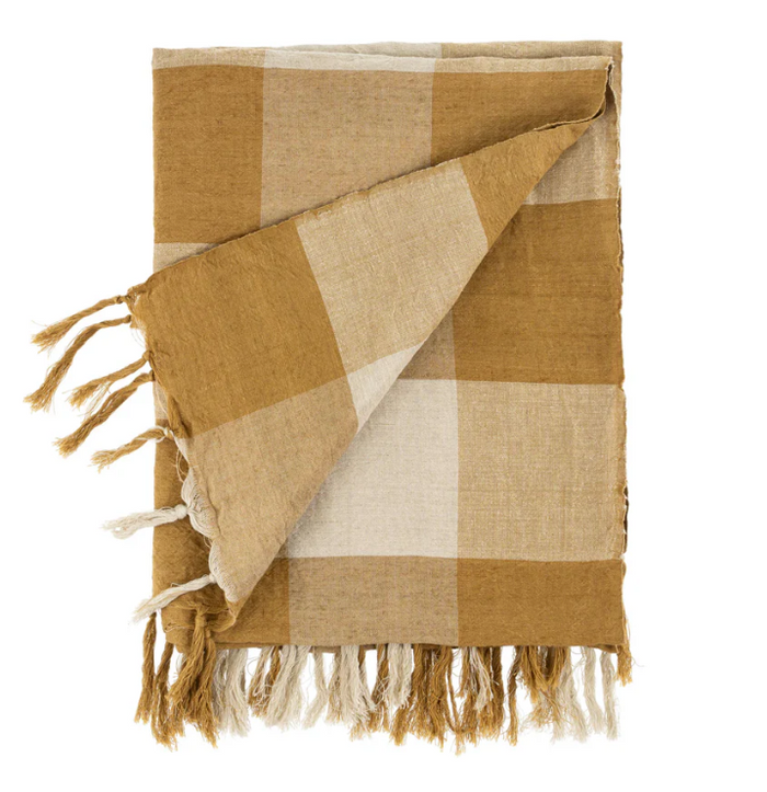 A toffee-colored linen-blend gingham throw with a check pattern and hand tied tassels at each end, displayed on a white background.
