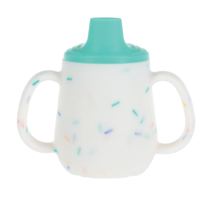 The 2-Handle First Training Cup | Aqua Confetti is a white silicone cup with colorful sprinkles, teal free-flow spout lid, and two easy-grip handles, designed for young children. Shown on a plain white background.
