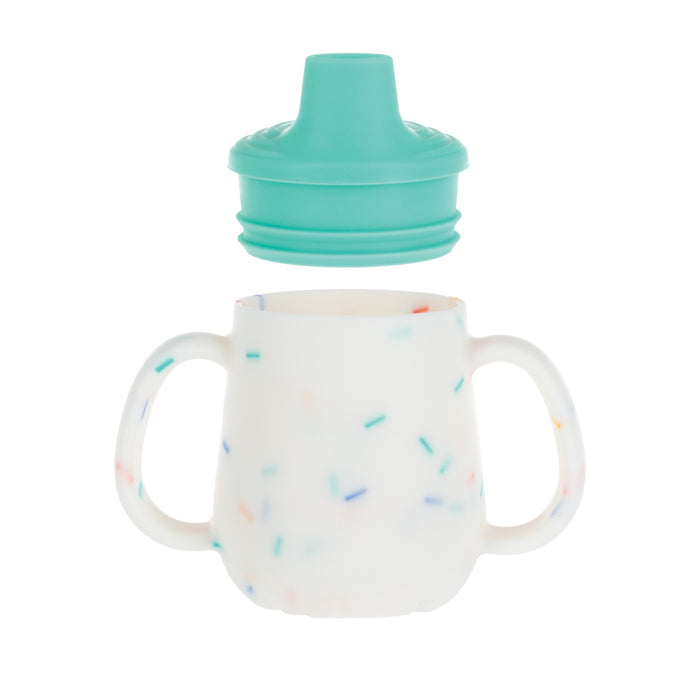 The 2-Handle First Training Cup | Aqua Confetti features a white silicone cup with colorful confetti specks, two easy-grip handles, and a teal lid, perfect for comfortable holding by little hands.