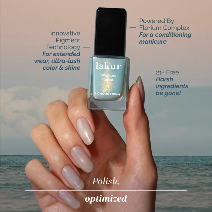 A manicured hand holds a bottle of LONDONTOWN’s Aegean Aqua nail polish against an aquamarine sky and sea backdrop, with key product features displayed nearby.