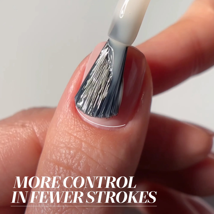 A close-up of a brush applying LONDONTOWN’s Aegean Aqua polish, its aquamarine sheen reminiscent of seawater, with the text "More control in fewer strokes" overlaid at the bottom.