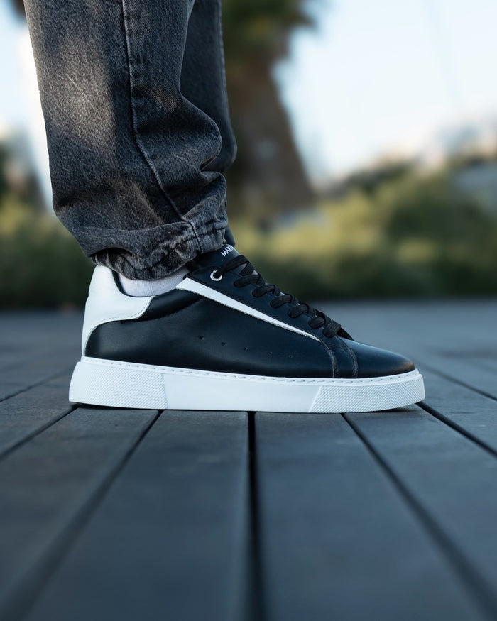 Martin Valen Axino men's black sneakers with white details, close side shot on pavement showing black laces and white platform sole