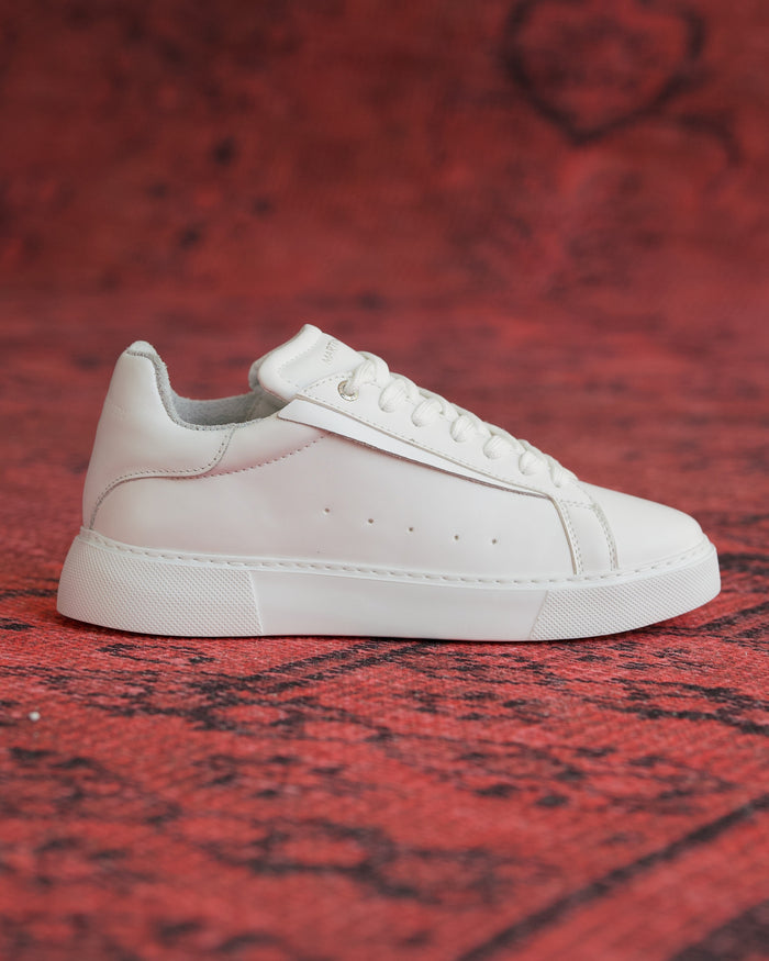 Martin Valen Axino men's casual white sneaker, side profile shot on a red patterned background showing low-top silhouette