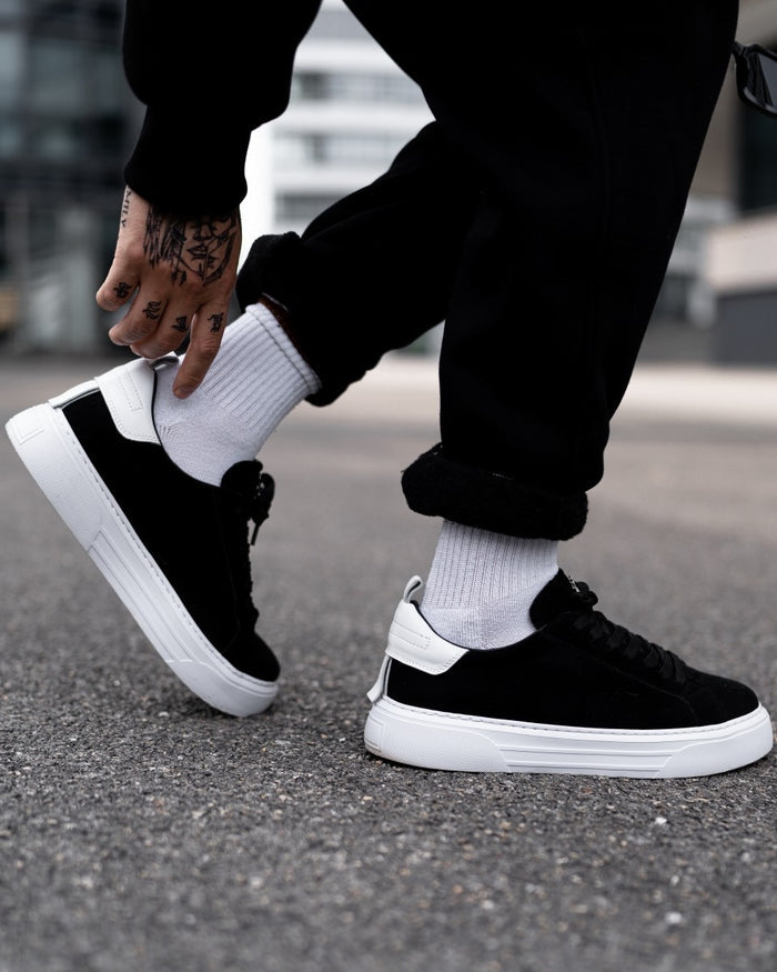 Martin Valen Bobe suede black and white sneakers worn outdoors, three-quarter rear view showing a stepping motion and thick platform sole
