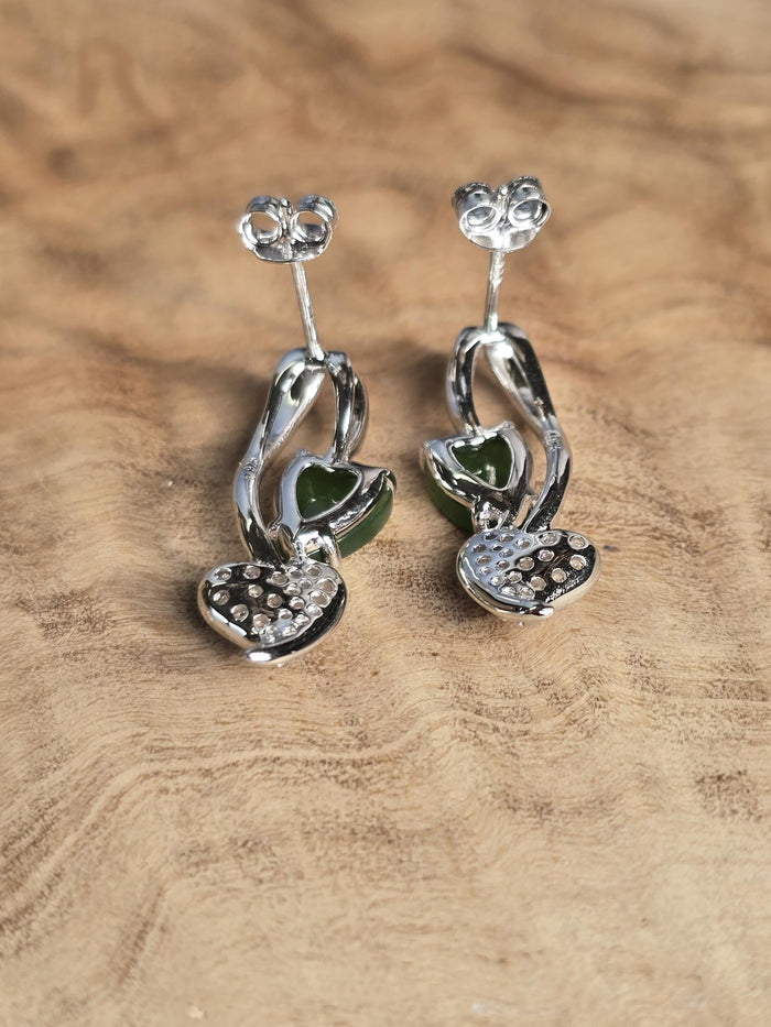Silver earrings with green gemstones on a wooden surface