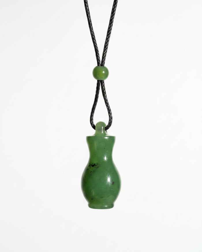 A small green jade bottle pendant on a black cord, white background