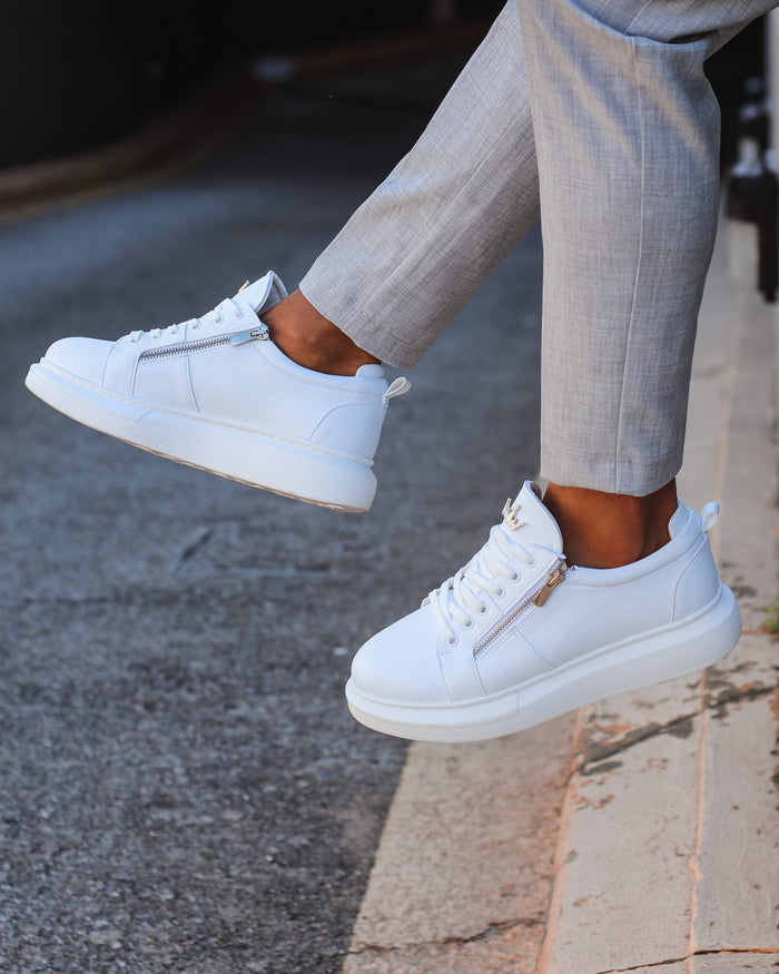 Martin Valen white chunky sneakers with side zipper, street-angle view showing ankle and grey tailored trousers
