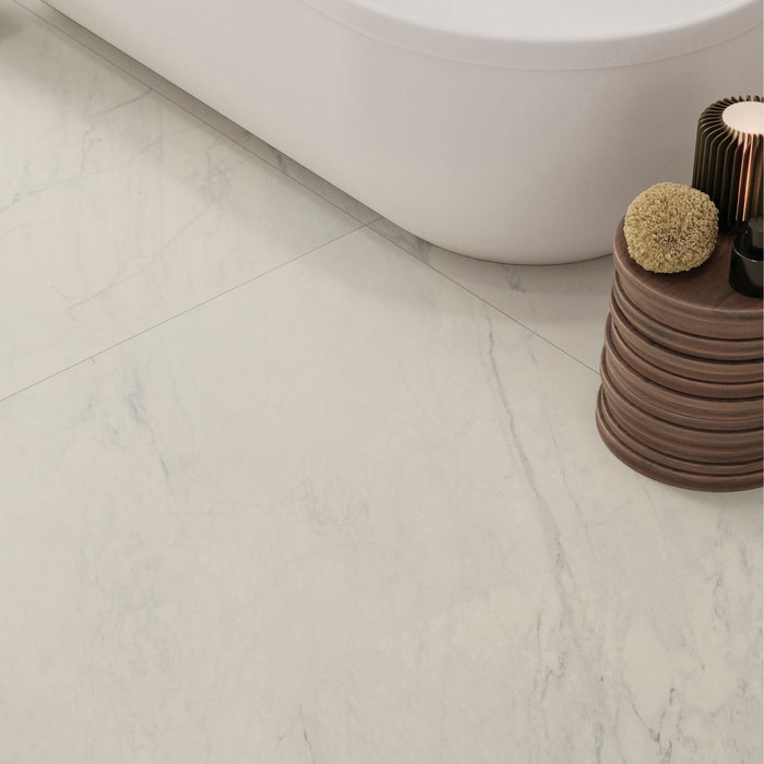 Close-up of a white marble effect tiled bathroom floor with a wooden stool and decorative items.