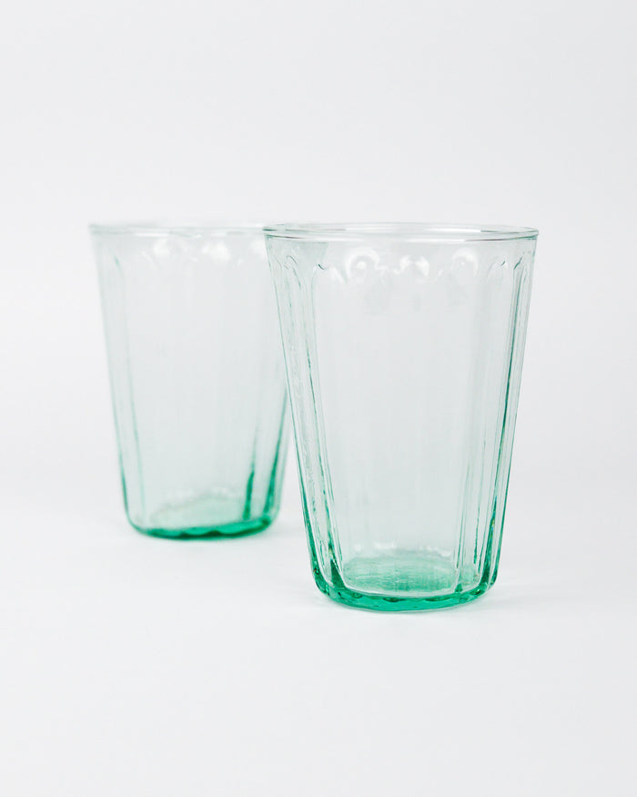 Two green glass tumblers on a white background