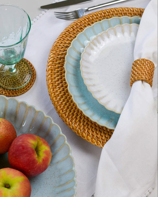 Table setting with blue and white scalloped edge plates, and a rattan charger plate.