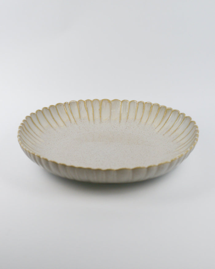 Large ceramic serving dish with decorative edge on a white background