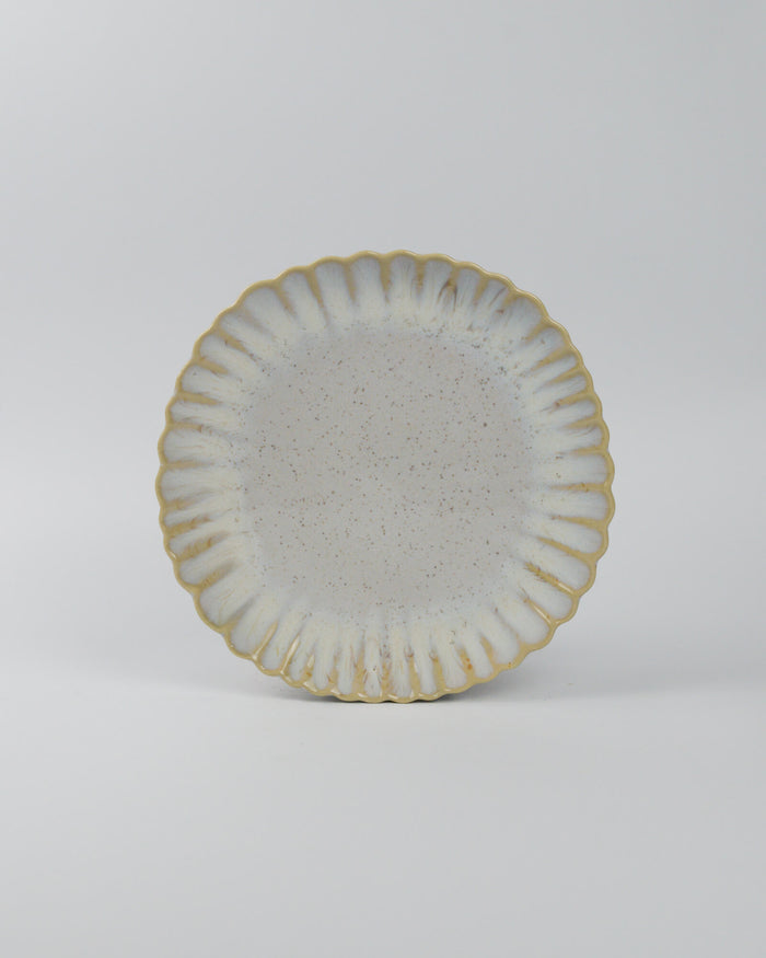 Ceramic salad plate with textured surface and scalloped edge on a white background