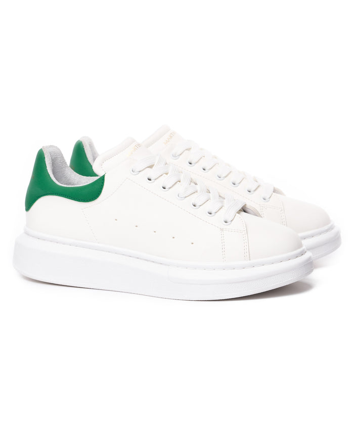 Pair of Martin Valen white chunky sneakers with green heel tabs, three-quarter view of laces