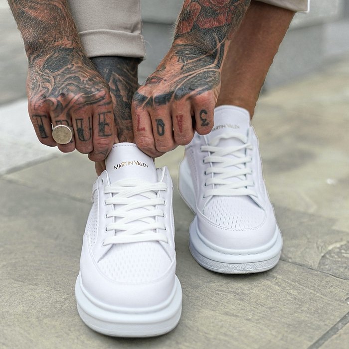 Martin Valen men's white sneakers front view while being laced, close-up on tongue with logo and tattooed hands