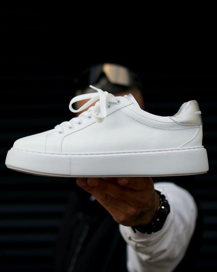 Martin Valen Iconic men's white-grey sneakers, side view held in hand showing chunky sole and grey heel tab.