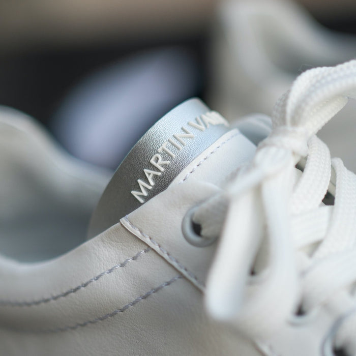 Martin Valen — close-up of white men's sneaker tongue with grey top and laces, angled view showing embossed logo