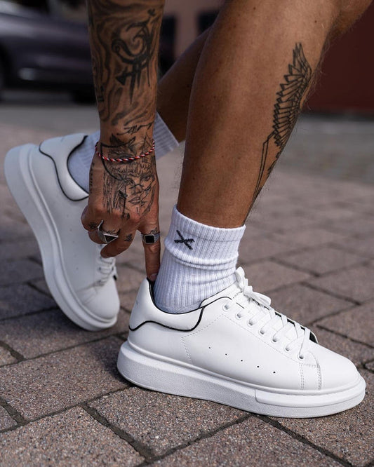 Martin Valen men's chunky white sneakers with black collar trim, worn outdoors as model adjusts laces