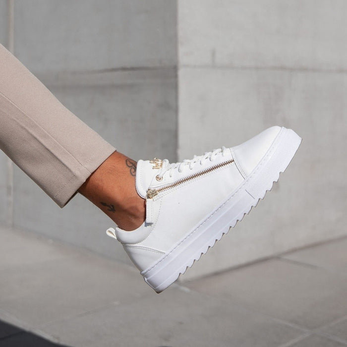 Martin Valen men's low-top white sneakers with gold side zipper, rear-side view worn with beige trousers
