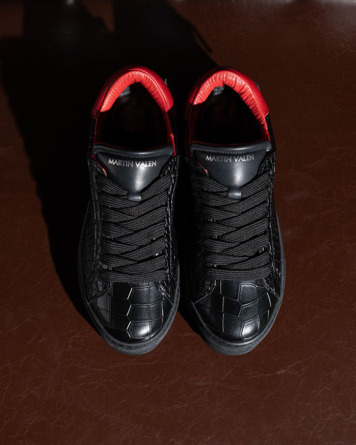 Martin Valen men’s low-top black sneakers with red collar, top-down view showing laces and textured toe pattern.