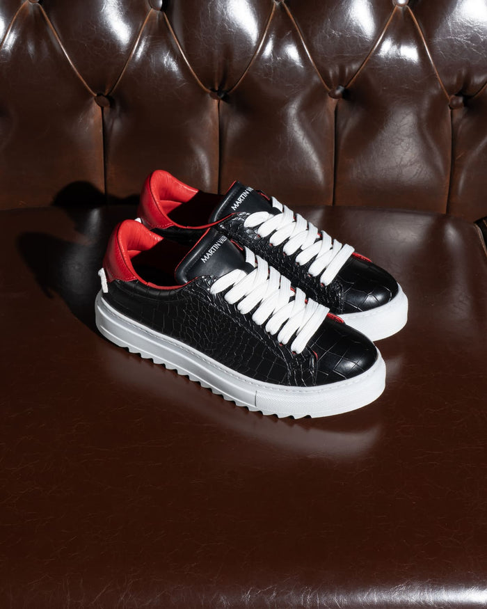 Martin Valen pair of men’s low-top black-white sneakers on brown leather sofa, white laces and red lining visible