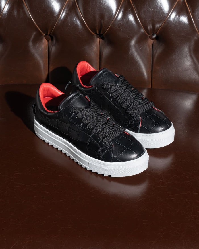 Martin Valen pair of men’s low-top black-white sneakers on brown sofa, black laces, white platform sole and red lining visible