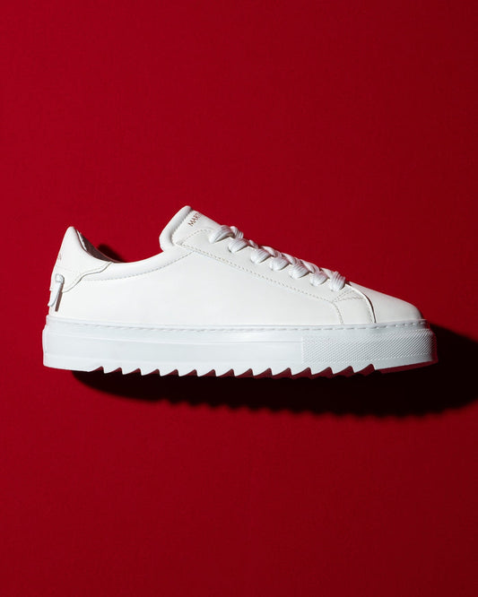 Martin Valen men's low-top white sneakers, side profile on red background showing chunky serrated sole.