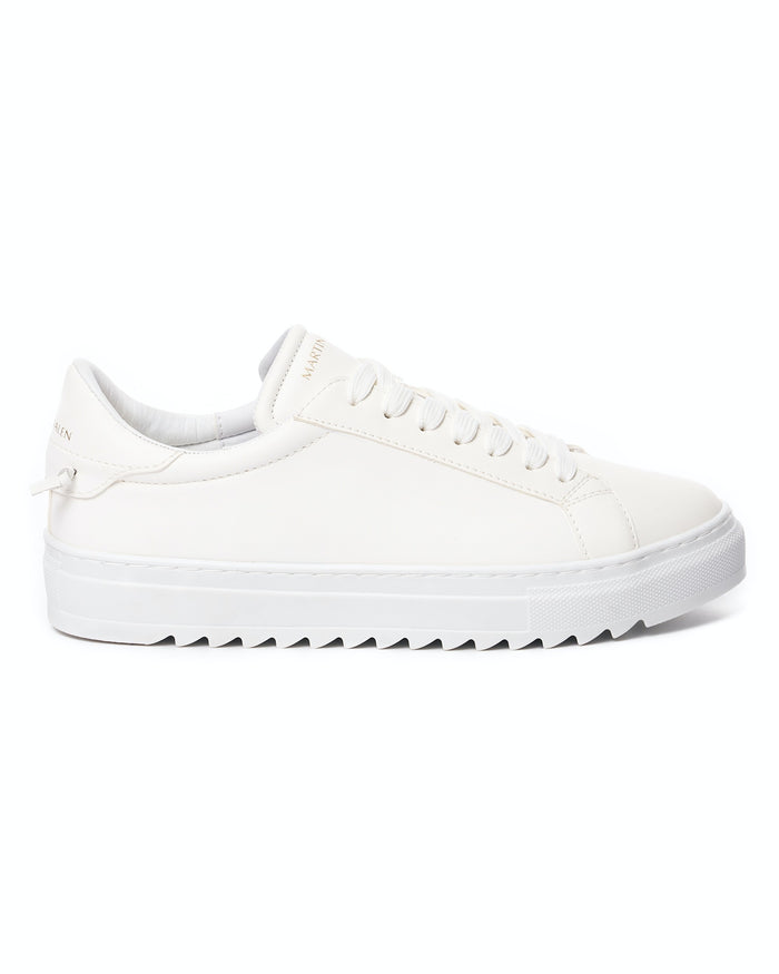 Martin Valen men's low-top white sneakers, side view held in a hand highlighting the thick platform sole and serrated outsole.