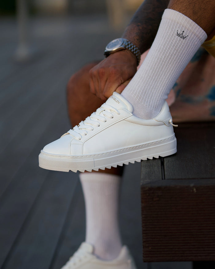 Martin Valen men's low-top white sneaker on foot, side view with sock visible and the Martin Valen name on the tongue