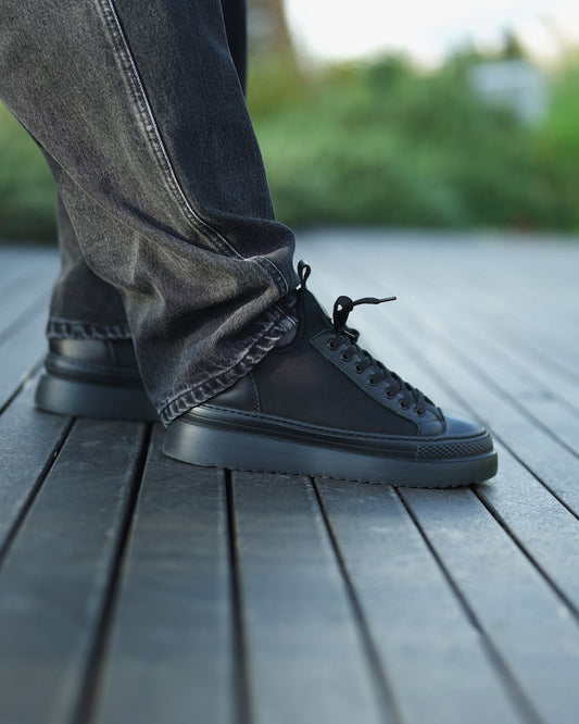 Martin Valen MonoFlux high-sole black scuba fabric sneaker, side view worn with grey jeans on a wooden deck
