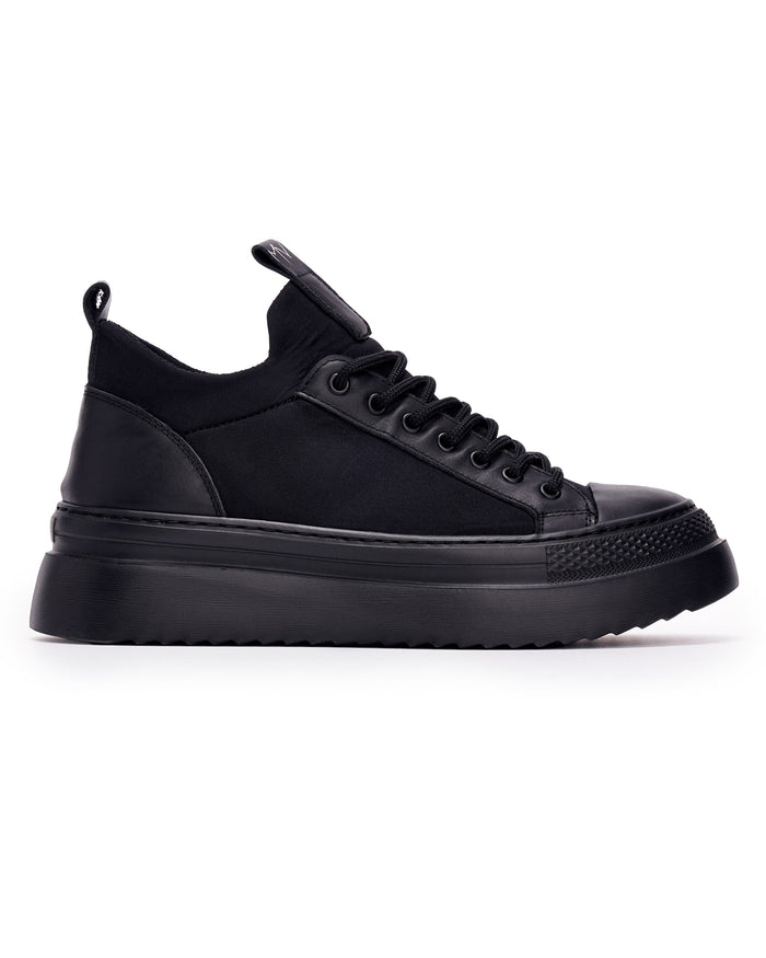 Martin Valen MonoFlux high-sole black scuba fabric sneaker, close side profile showing chunky black sole and MV logo pull tab