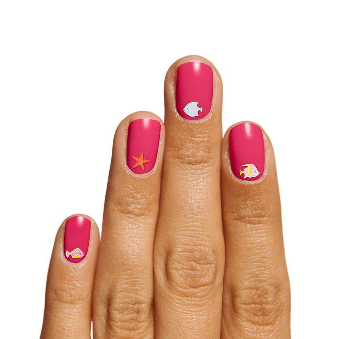 Hand with pink manicure featuring Nail Paradise tropical fish and starfish stickers on medium skin tone