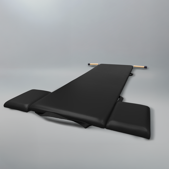 Black Gratz Pilates low rigid mat with wooden pole and side platforms.