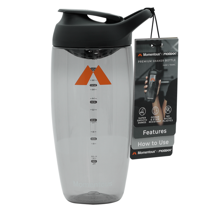Clear shaker bottle with black lid, orange triangle logo, measurement markings, and attached instruction tag.