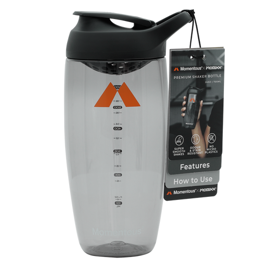 Clear shaker bottle with black lid, orange triangle logo, measurement markings, and attached instruction tag.