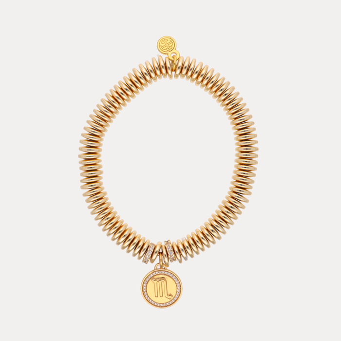 Gold coil bracelet with Scorpio symbol charm on a white background
