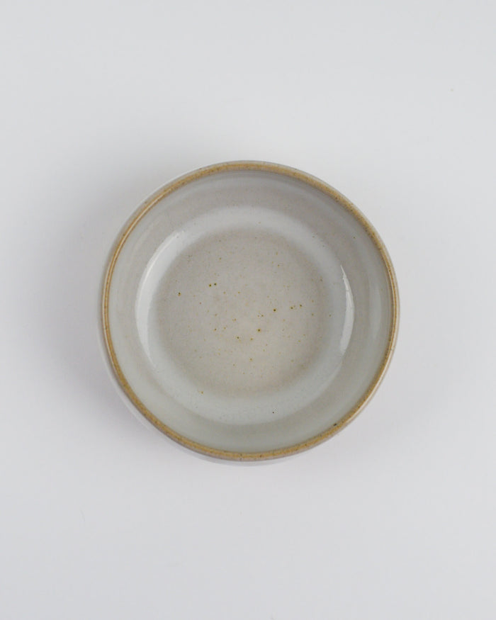 Ceramic dipping bowl with a textured rim on a white background