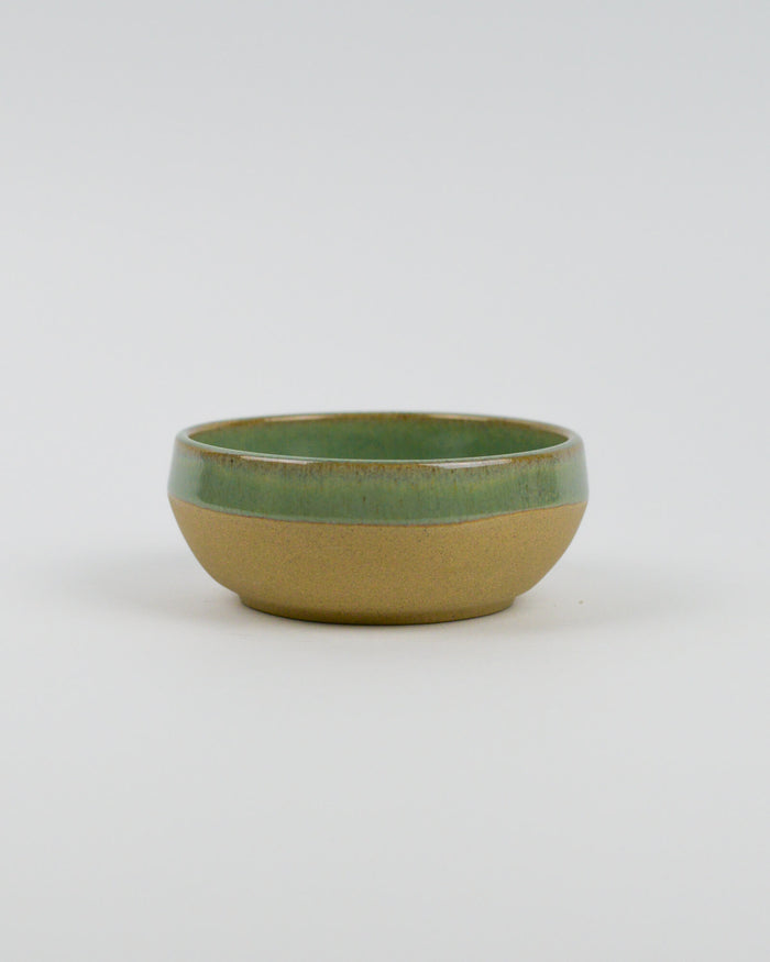 Ceramic bowl with green top and beige bottom on a white background