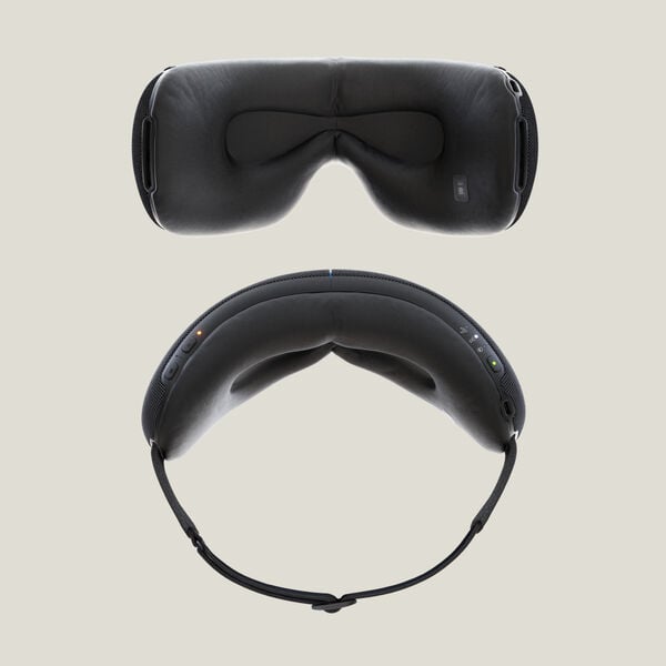 Top and bottom views of a sleek black wellness device designed for eye and facial recovery, labeled SmartGoggles 2 | Therabody, featuring soft cushions and adjustable straps.