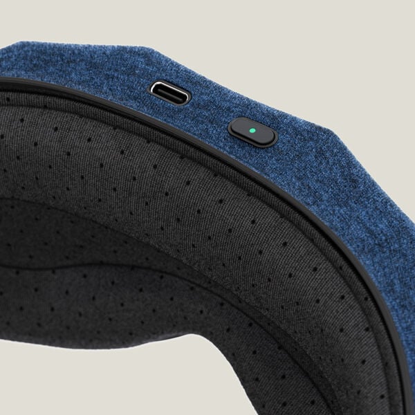 Close-up of a textured fabric Therabody Sleepmask | Therabody showing a power button with an indicator light and a USB-C charging port for wellness and recovery.