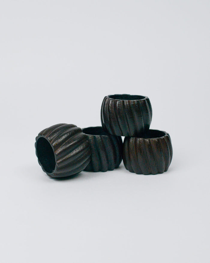 Set of  four dark wooden ribbed napkin ring on a white background