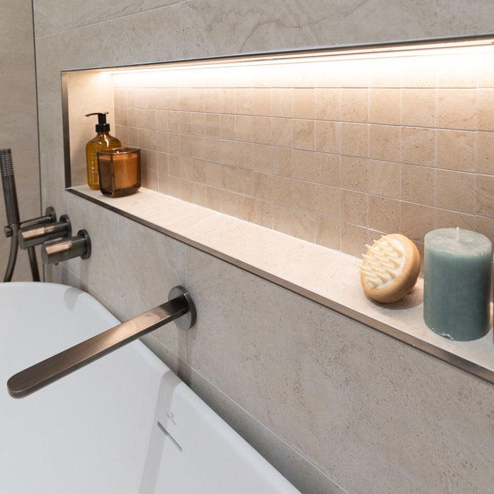 Bathroom setting with a bathtub, tap and shelf with toiletries.