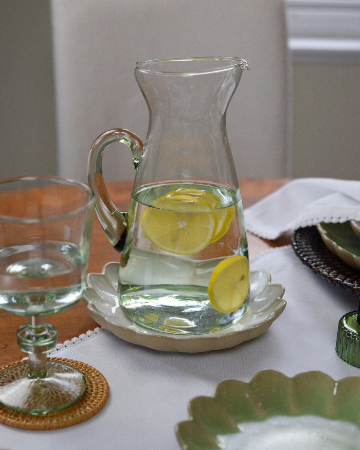 Clear glass pitcher with lemon slices on a white tablecloth